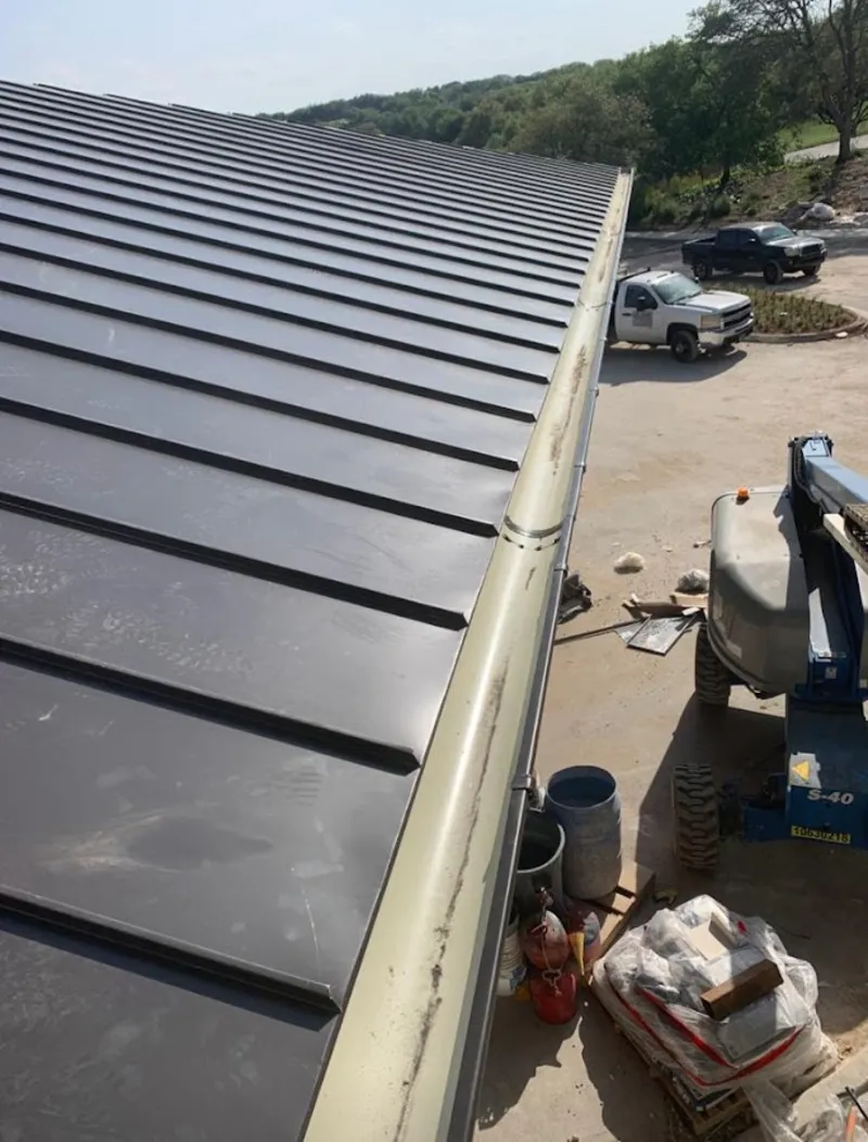 Standing seam panel and gutter detail on a metal roofing jobsite in Bonham